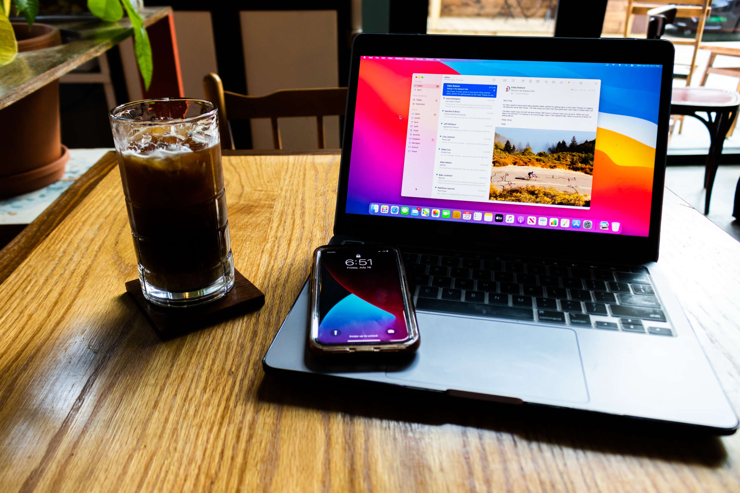 An iPhone and a laptop with Mac notes app open in cafe.
