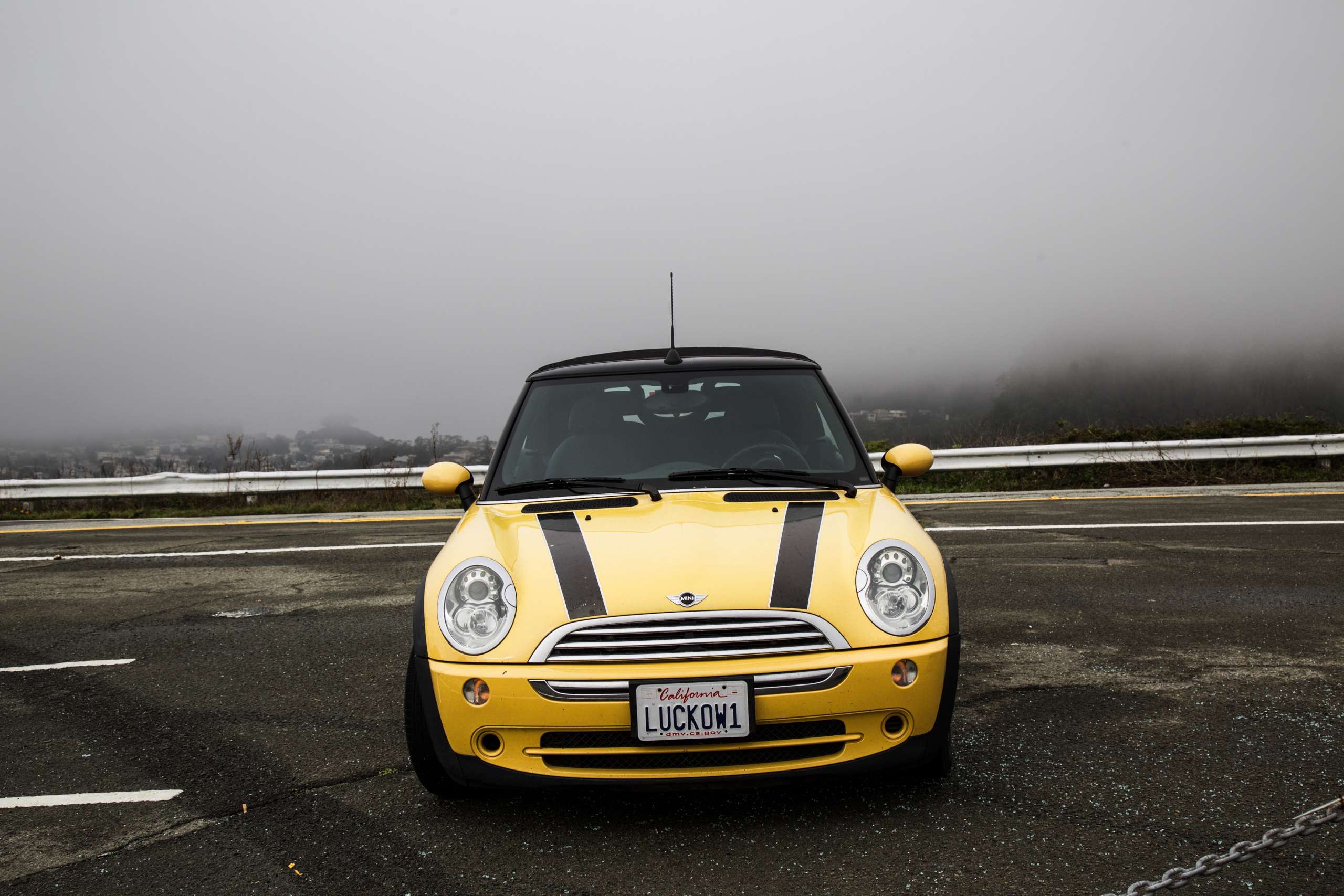 Yellow Mini Cooper head-on in front of fog.
