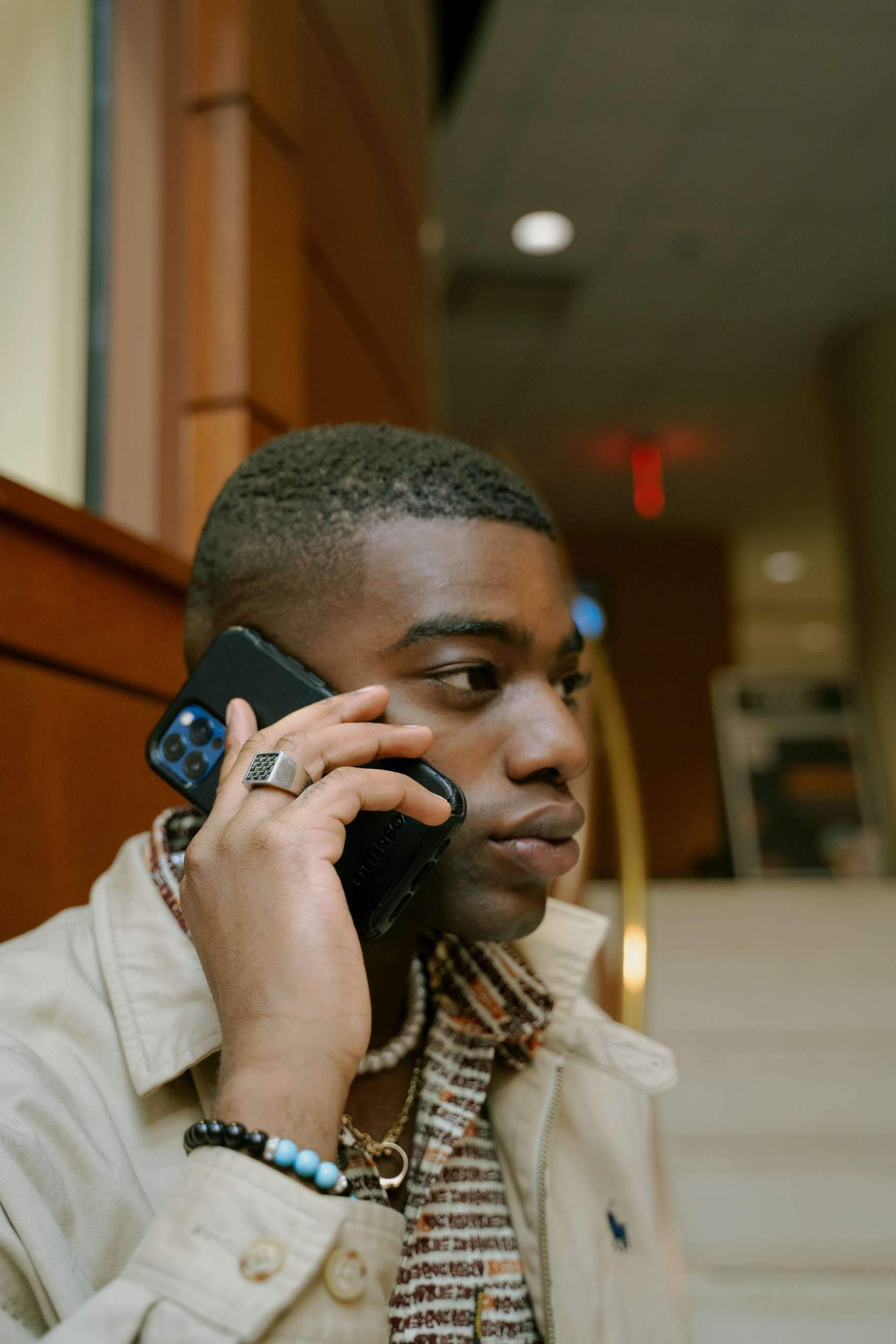 Young black man in profile speaks on cellphone.
