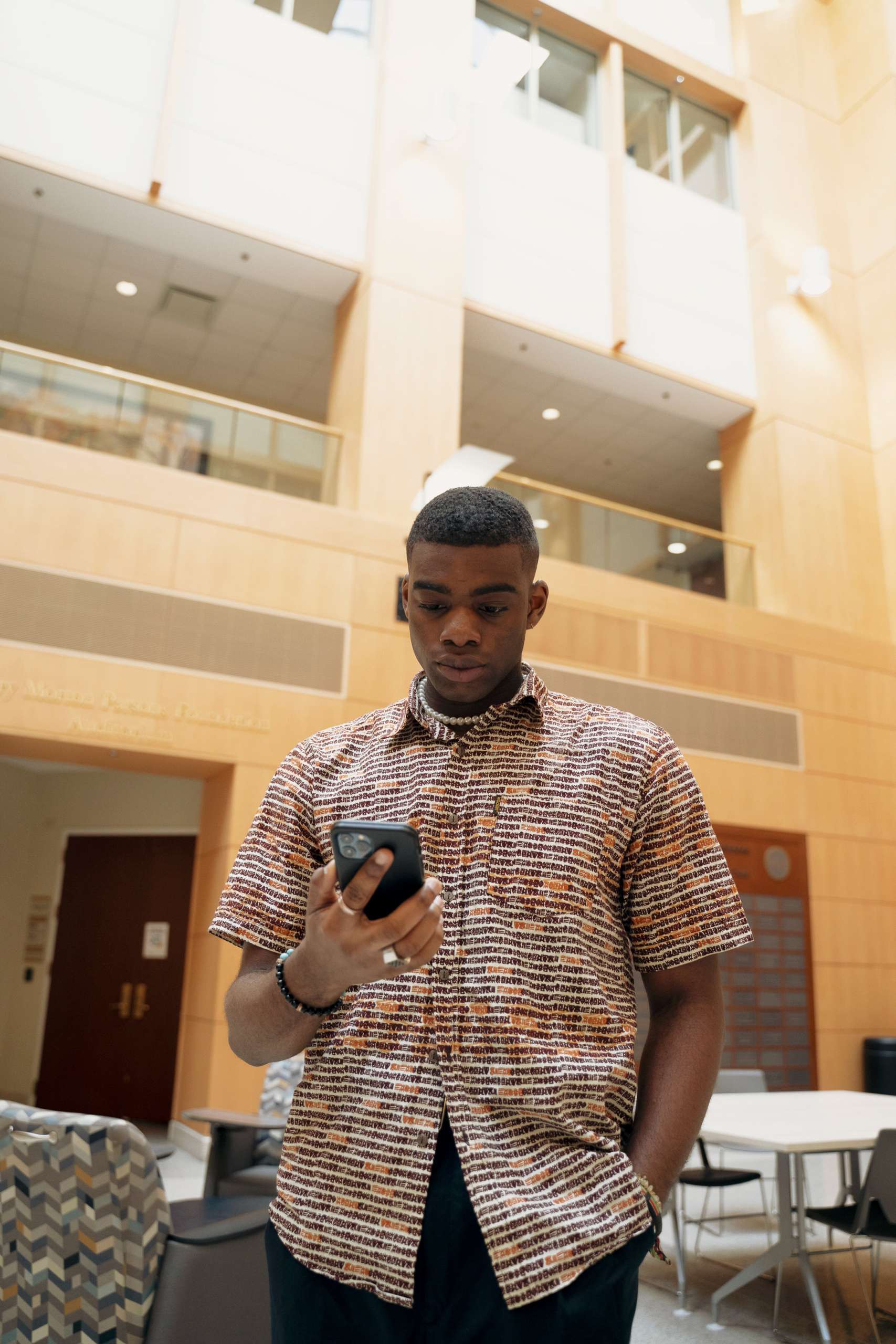 Young black man looks down at his phone.