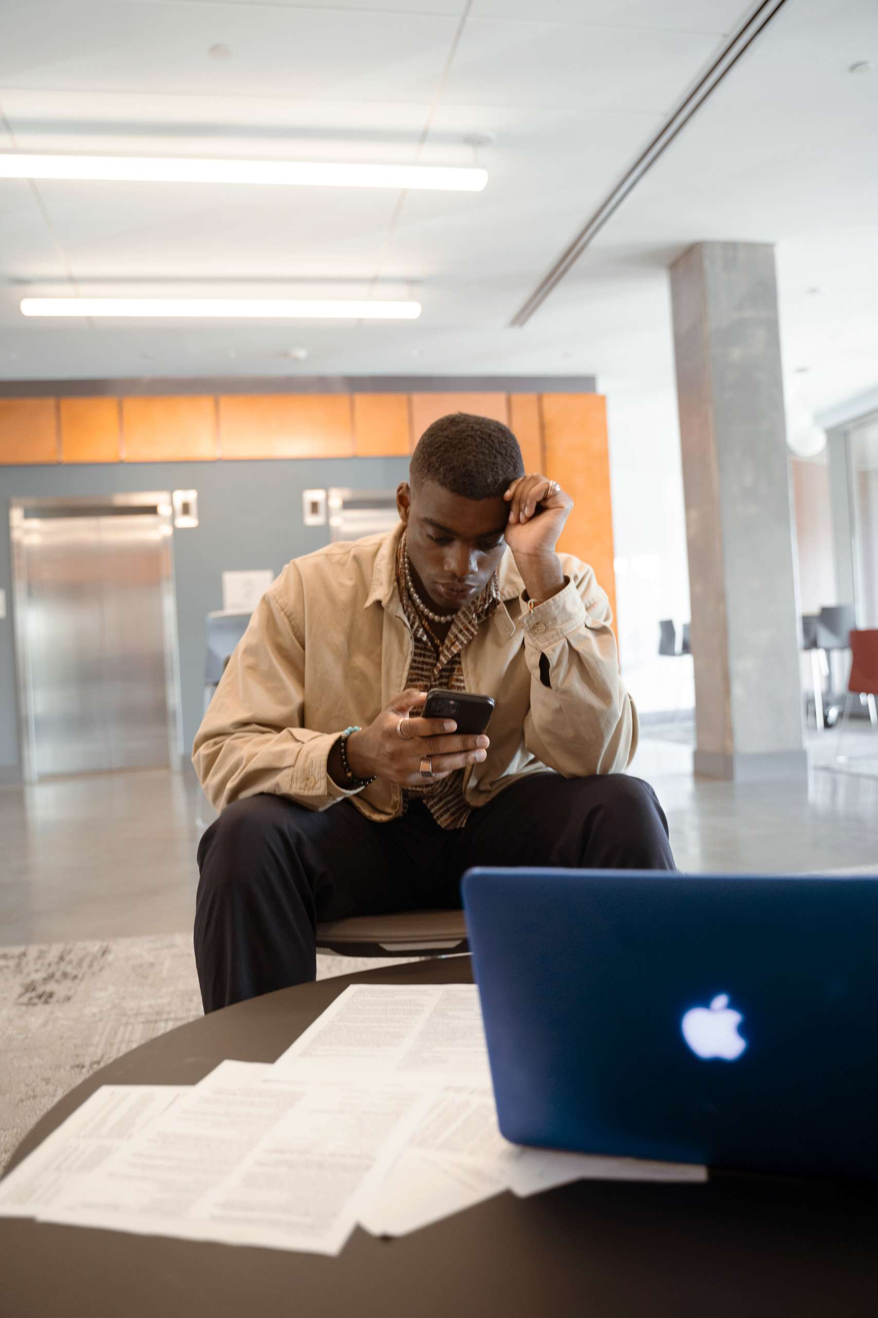 Young black man sits looking at his phone.